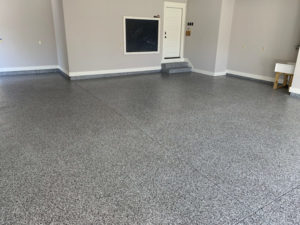 An empty garage has a gray, full-broadcast epoxy floor coating newly installed.
