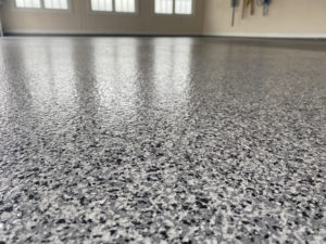 Black, grey, and white speckled epoxy basement floor coating.