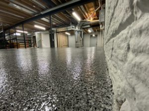 Close up of dark gray textured epoxy floor coating in a basement