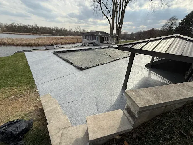 Pool deck with full flake epoxy coating, covered pergola, and a lake view
