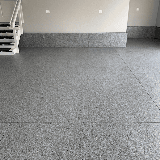 Gray full flake epoxy garage floor with matching baseboard after coating installation