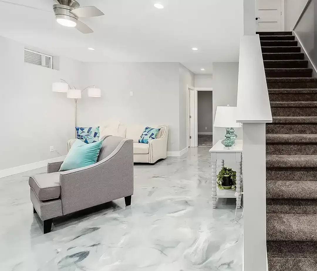 Finished basement living room with a white and gray marbled metallic epoxy floor, sofa and carpeted stairs