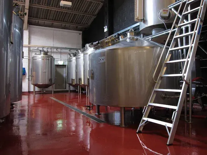 Brewery with a red epoxy floor coating, stainless steel tanks and a ladder