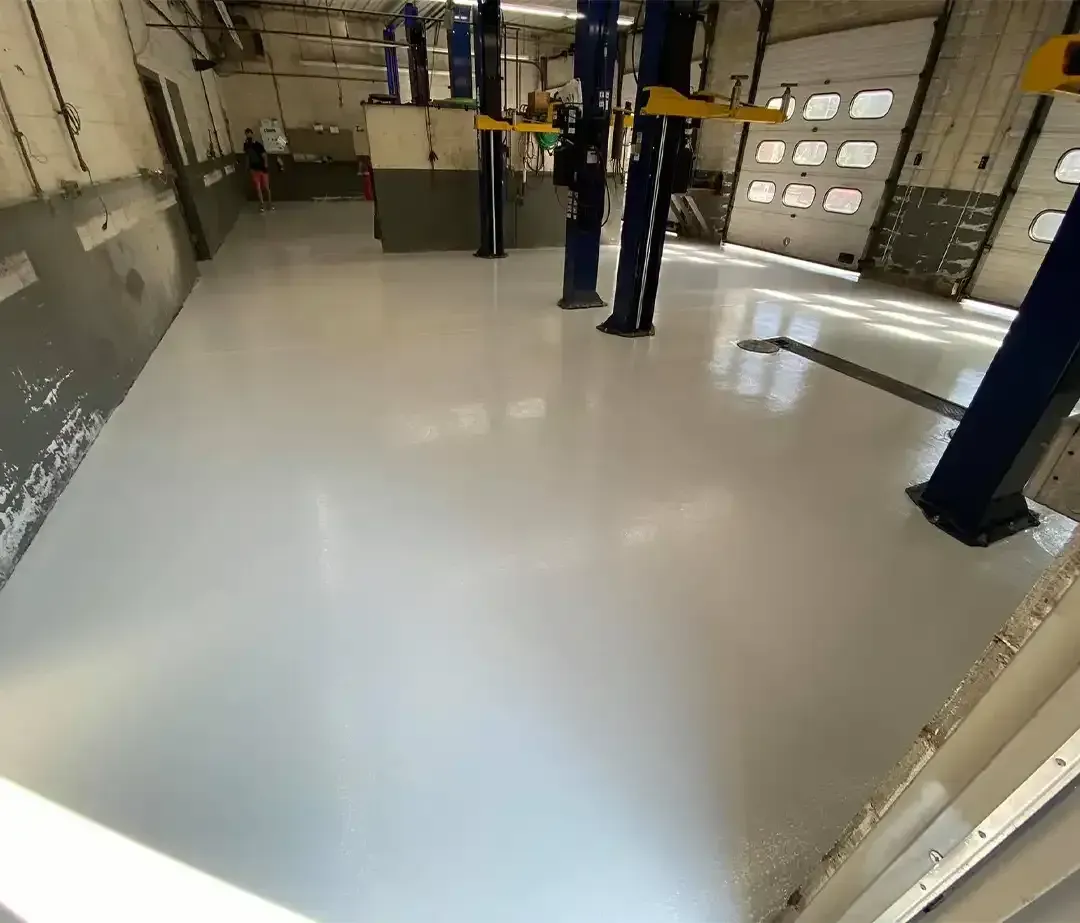 Commercial auto shop bay with vehicle lifts on a glossy gray epoxy floor coating