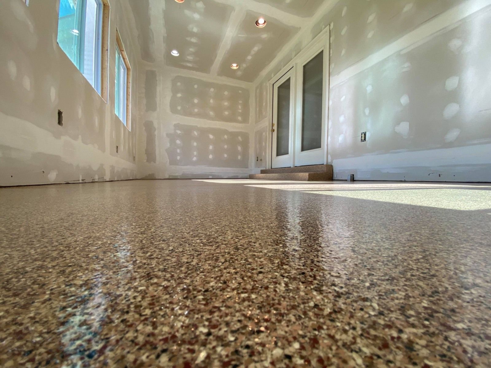 Room under construction with taped drywall and a tan and red full flake epoxy floor