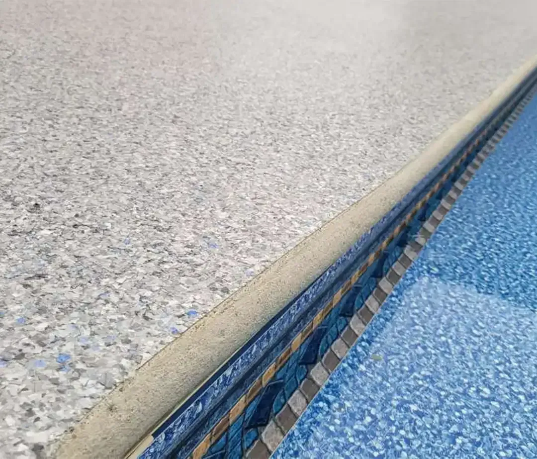 Full flake epoxy pool deck edge next to a blue and gray tiled pool waterline