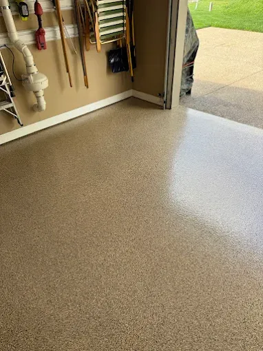 Garage with tan full flake epoxy floor, tools on the wall, and open doorway to a yard