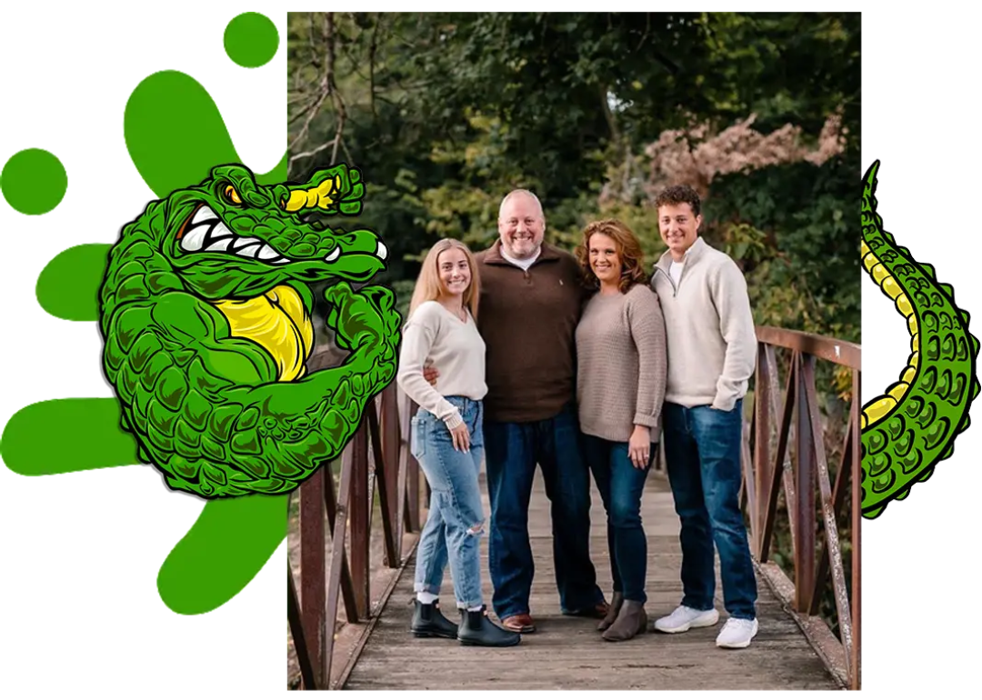 Family of four posing on a wooden bridge, flanked by green alligator mascot graphics