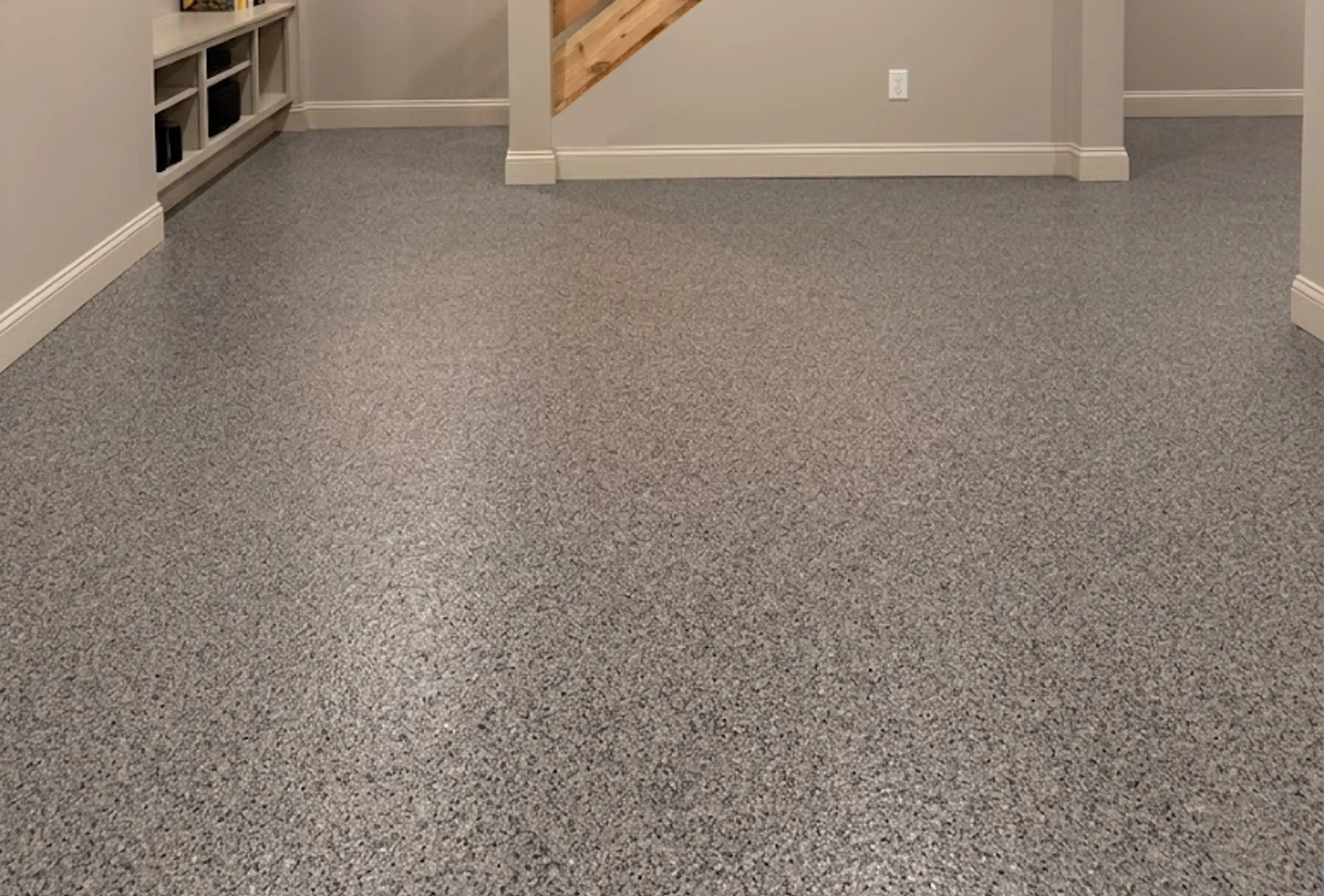 Basement hallway with built in shelving and a staircase on a full flake gray epoxy floor