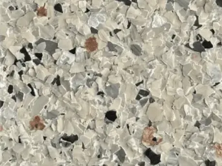 Close-up of a full flake epoxy floor in cream, gray, black, and rust colored chips