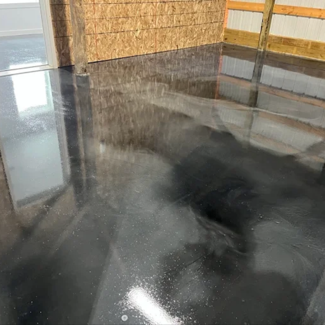 Glossy black and grey epoxy floor coating reflecting overhead light in an industrial space