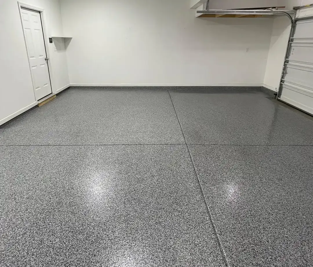 Empty two-car garage with a gray full flake epoxy floor, white side door and overhead shelving