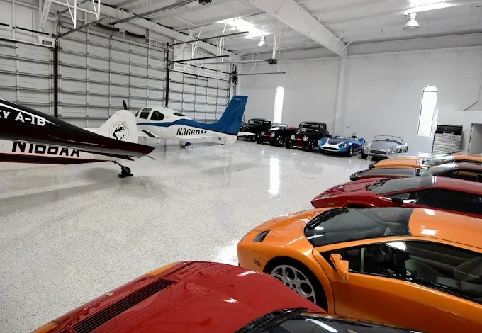 Airplane hangar with glossy epoxy floor coating, a private plane, and luxury sports cars