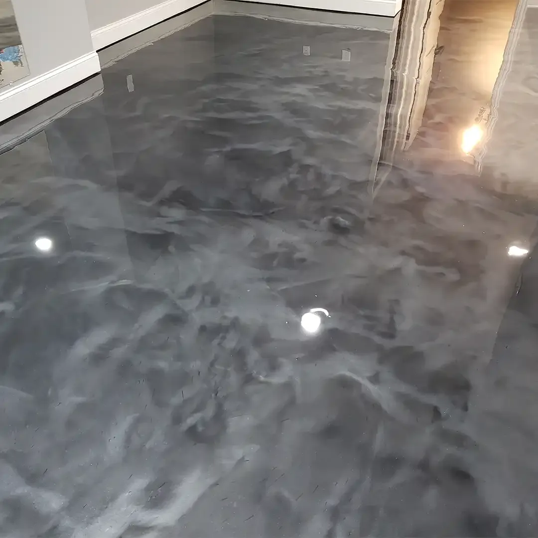Dark charcoal metallic epoxy floor with a high gloss swirled finish beside a white door and exposed wood framing