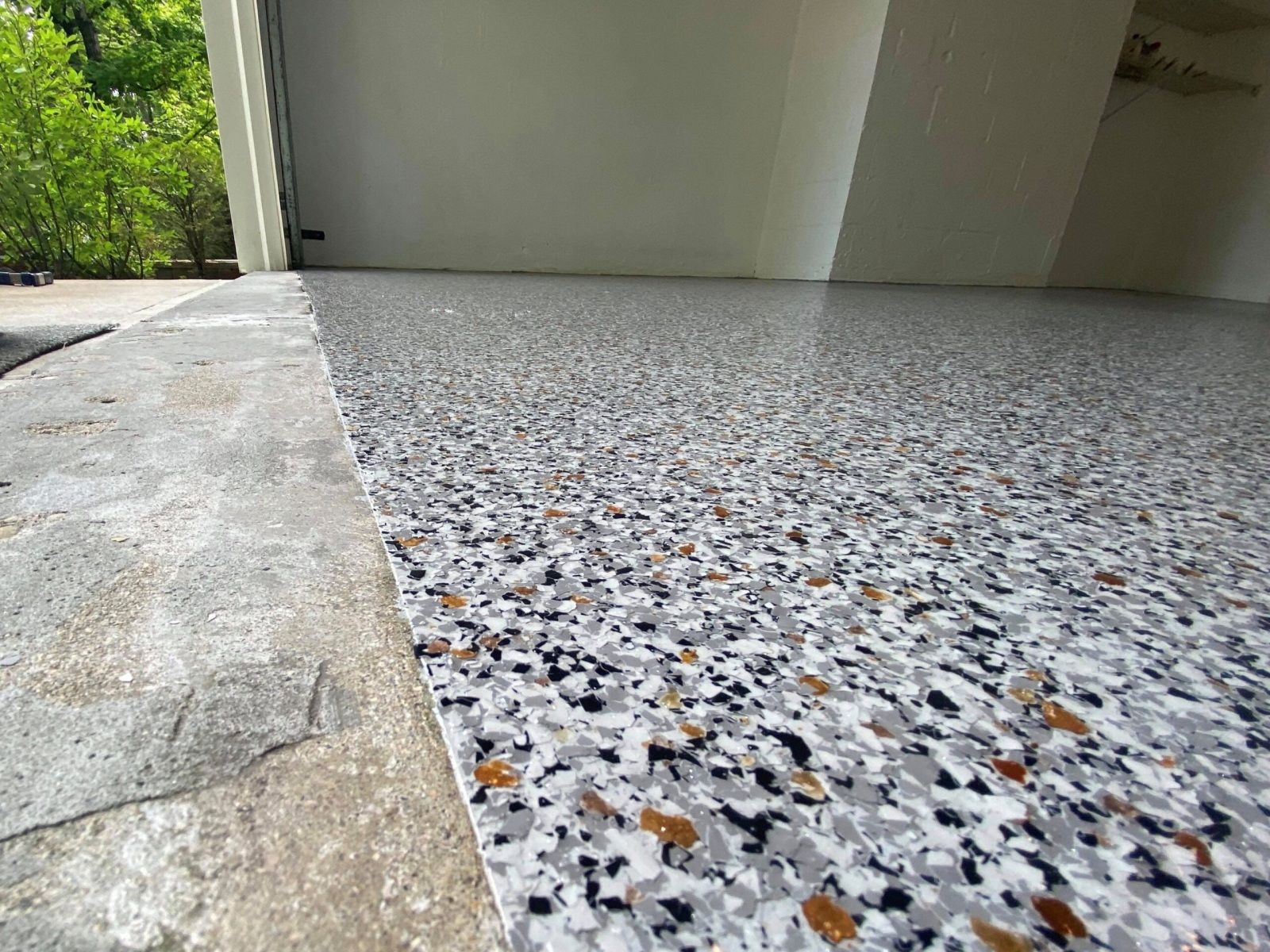 Full flake epoxy garage floor viewed low angle with the driveway visible outside