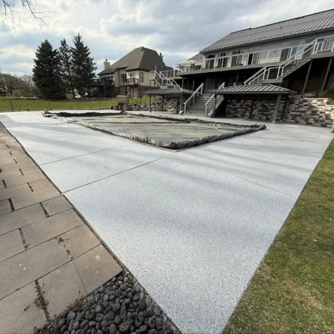 Concrete patio with a covered pool, stone walkway, and a large house in the background